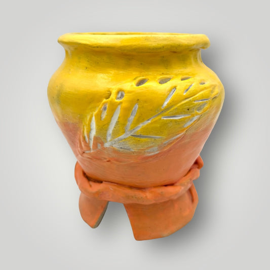 This delightful ceramic planter features a two-tone design. The upper portion boasts a vibrant yellow, while the lower section showcases a orange finish. The yellow area is adorned with intricate leaf-like patterns etched into the surface, adding texture and visual appeal.&nbsp; Overall, it’s a charming piece for displaying your favorite plants.&nbsp;